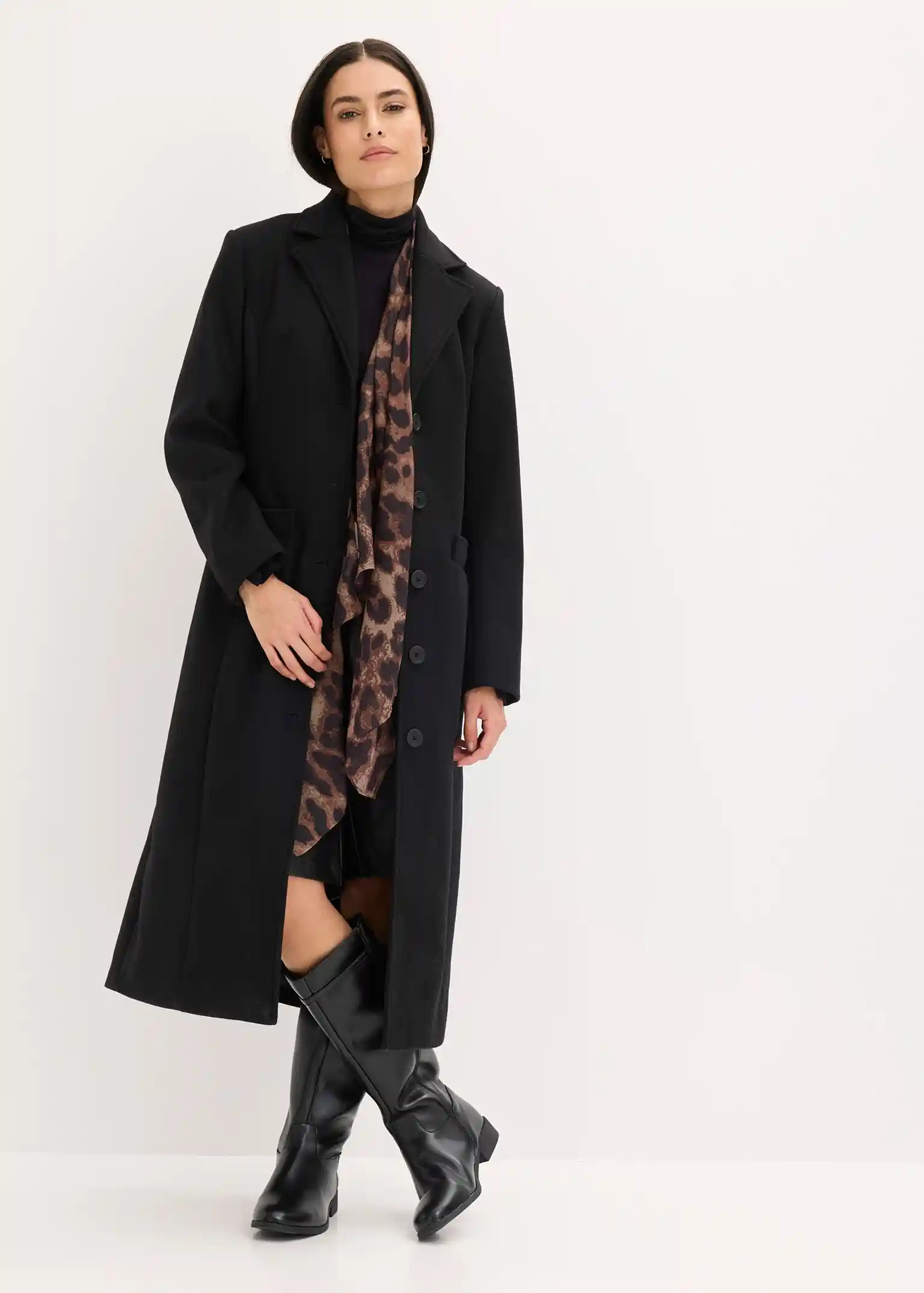 Woman in a black wrap coat with a leopard-print scarf, black turtleneck and knee-high boots