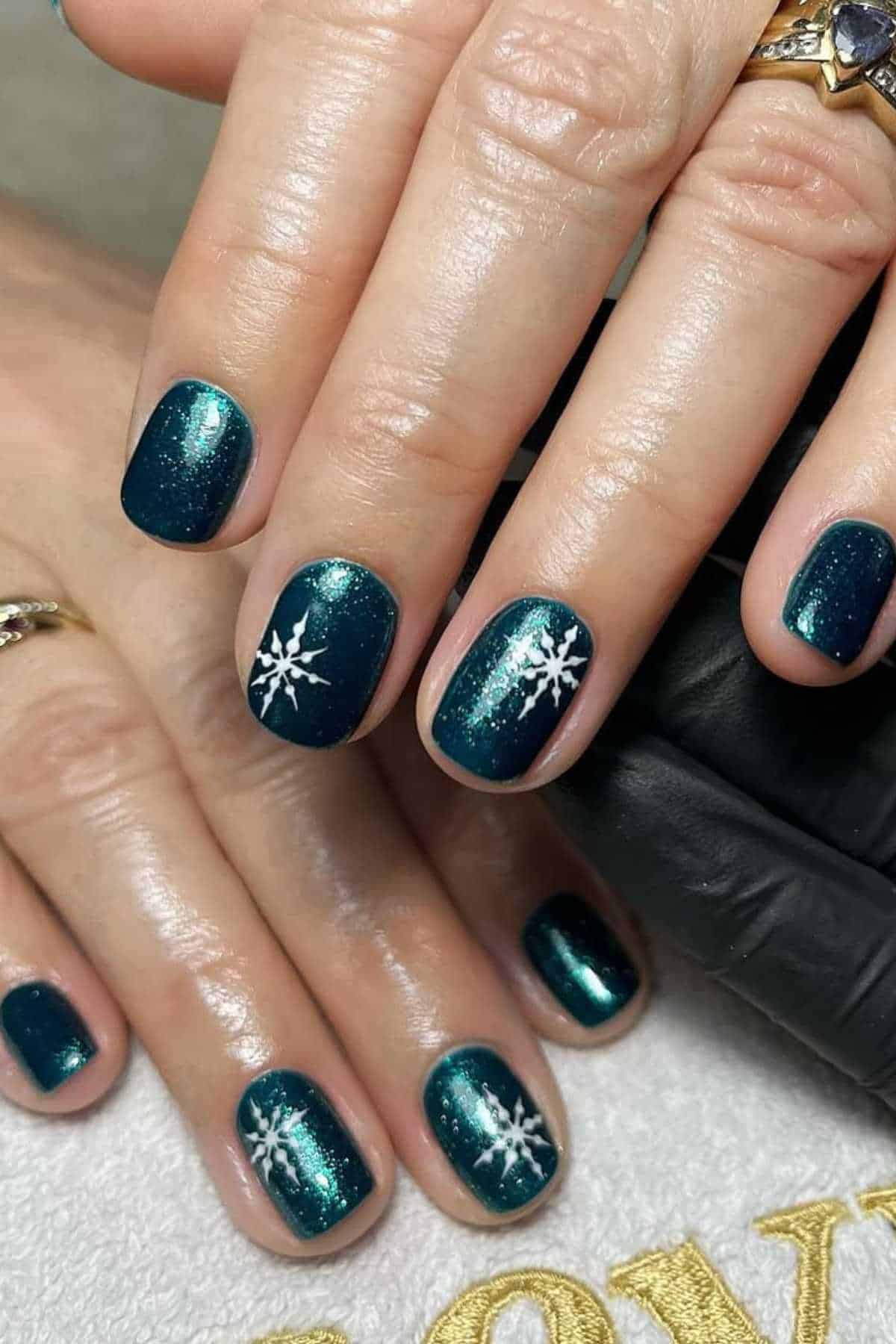 Short nails in shimmery deep teal green with white snowflake art
