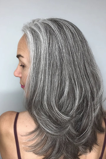 Medium-length layered hair in natural salt-and-pepper gray, side view