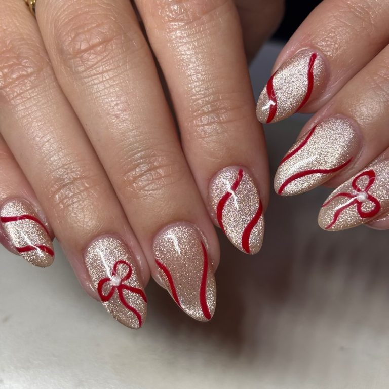 Medium almond champagne-glitter nails with red ribbon swirls and bow nail art
