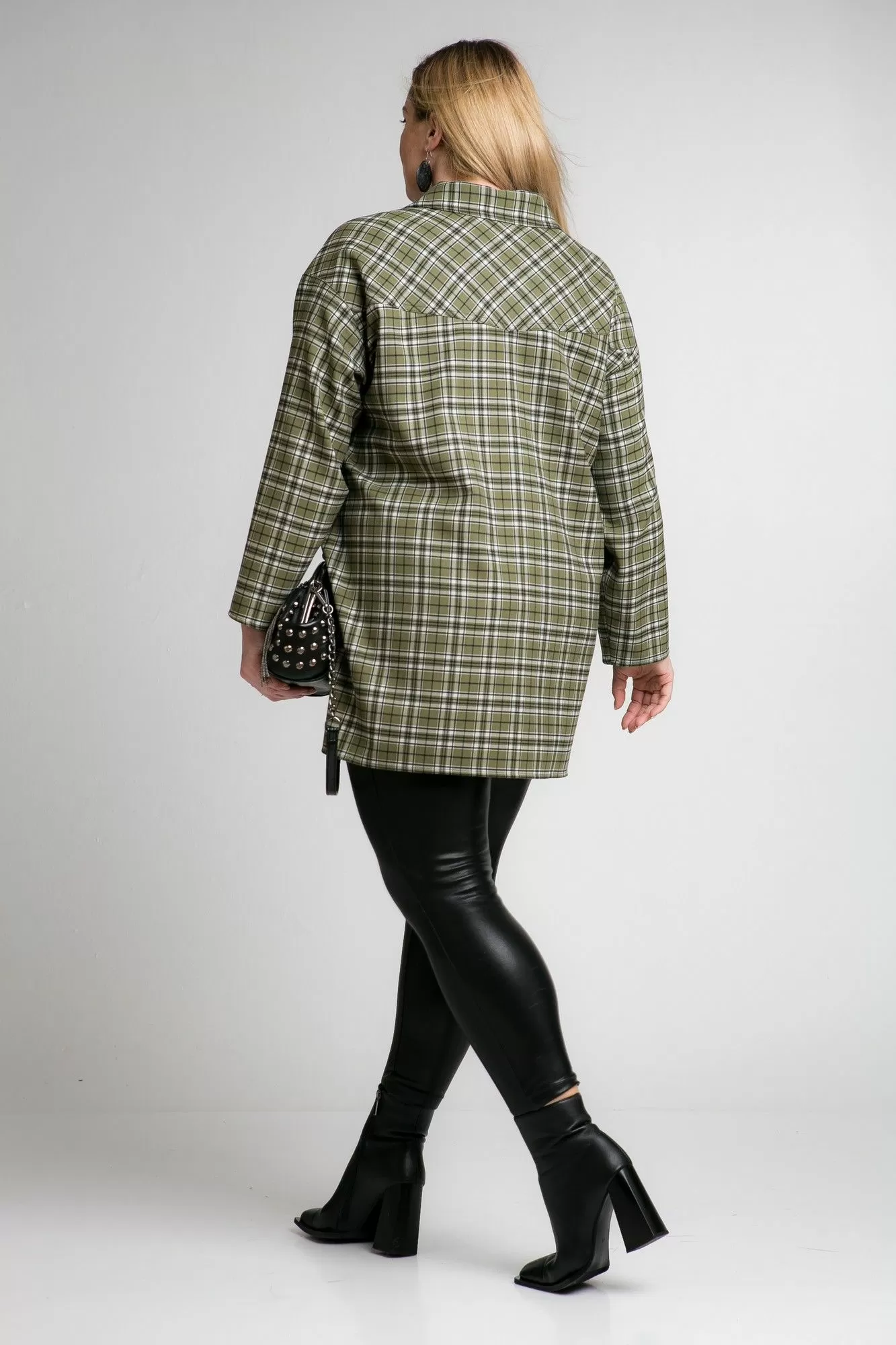 Woman wearing an oversized green plaid shirt, black leather leggings and black block-heel ankle boots