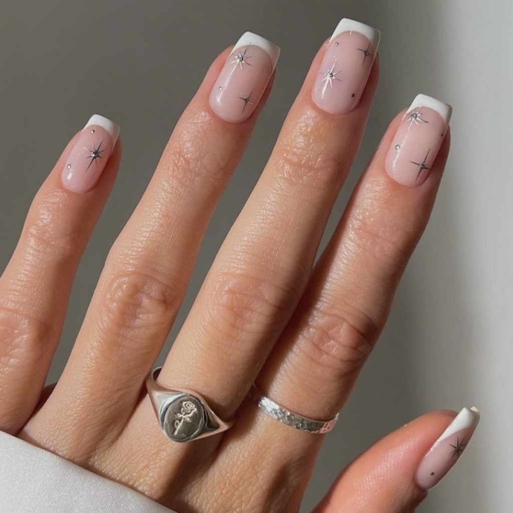White French tips on square nails with silver starburst sparkle art