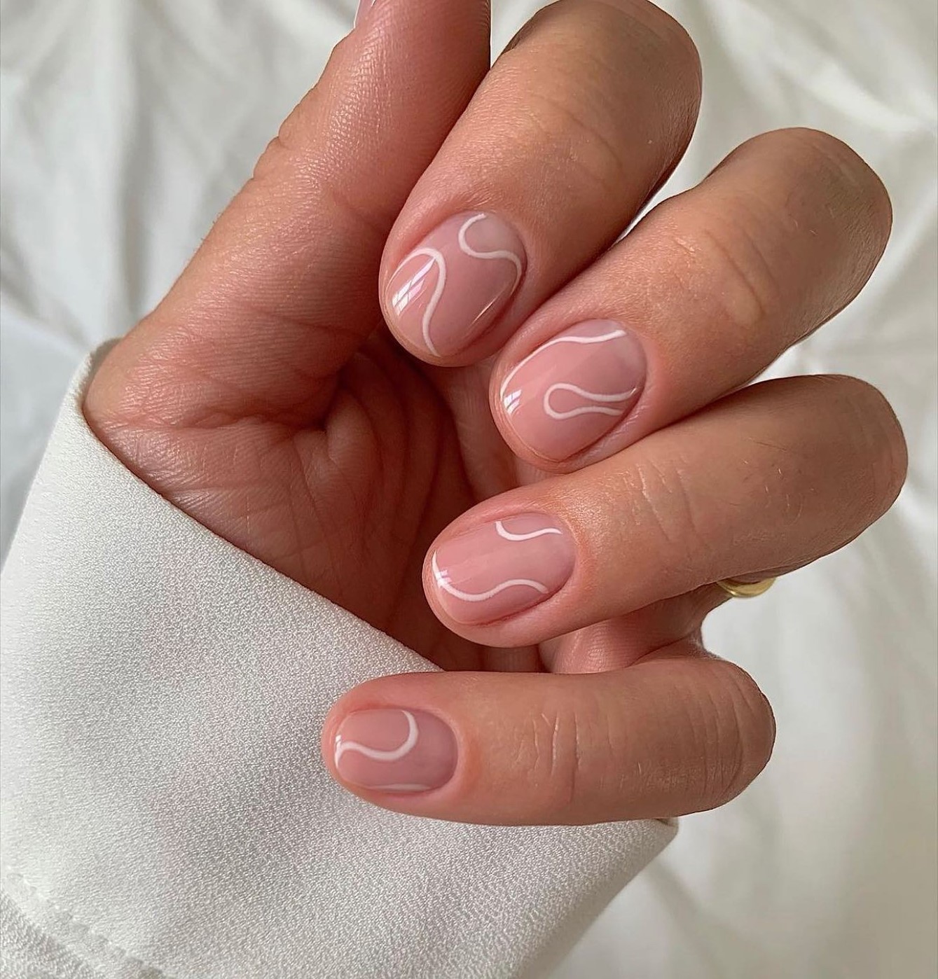 Short oval blush pink nails with white swirl nail art