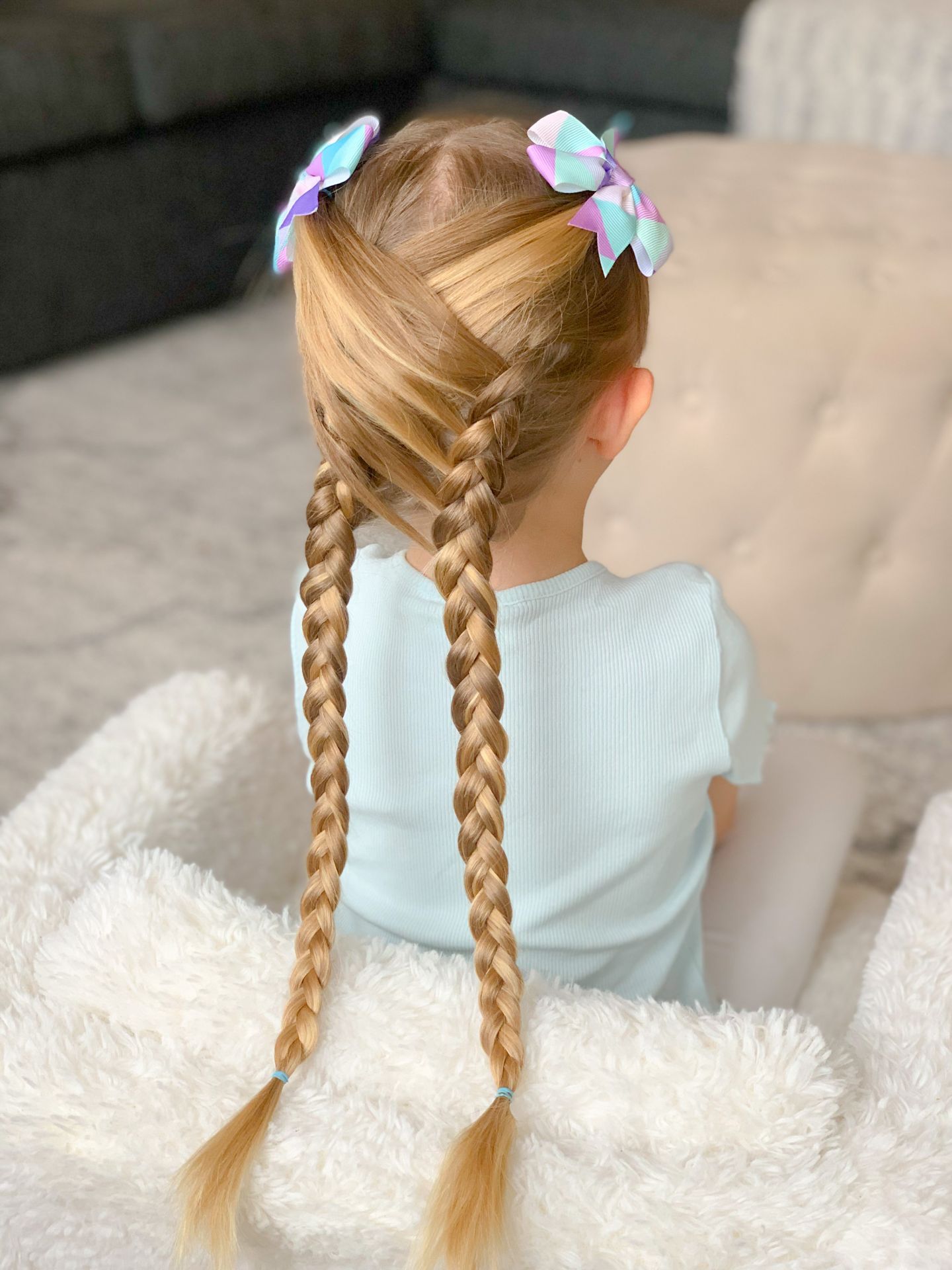 Little girl seen from behind with double french braids tied with pastel ribbon bows