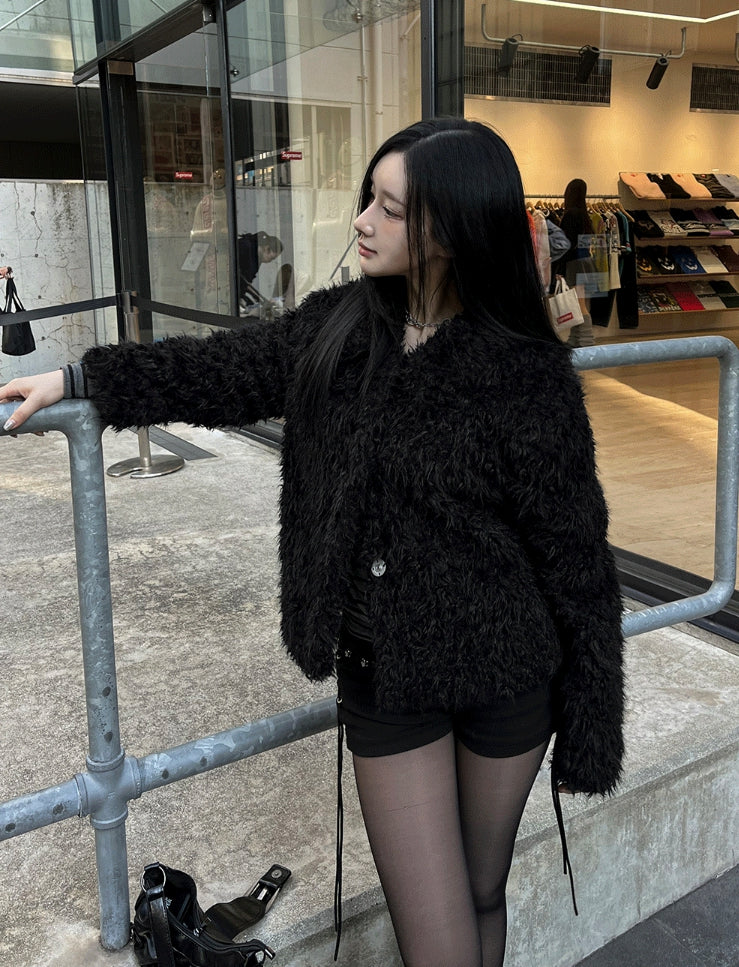Woman in a black shaggy teddy jacket with black shorts, black tights and a black bag