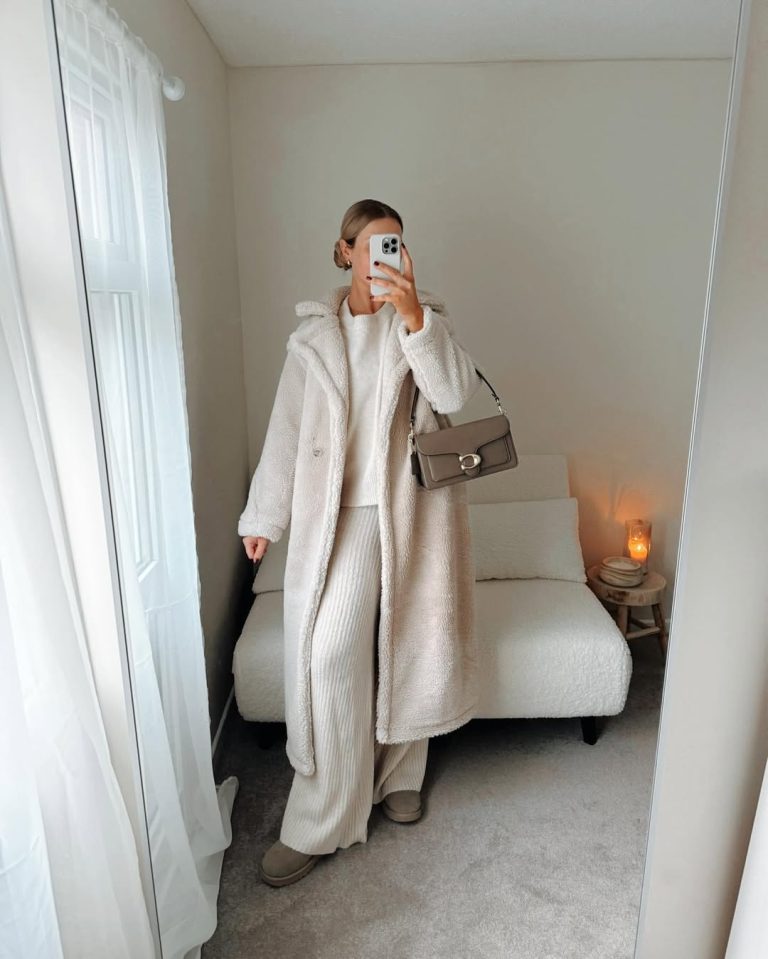 Woman taking a mirror selfie in a cream teddy coat over a cream knit co-ord with Ugg boots