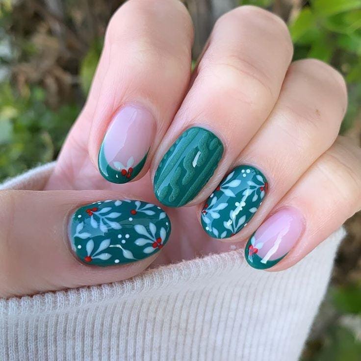 Deep green nails with white botanical holly patterns, a cable-knit accent and holly French tips