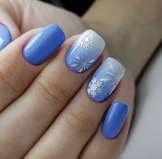 Cornflower-blue nails with white snowflake decals on the accent nails.
