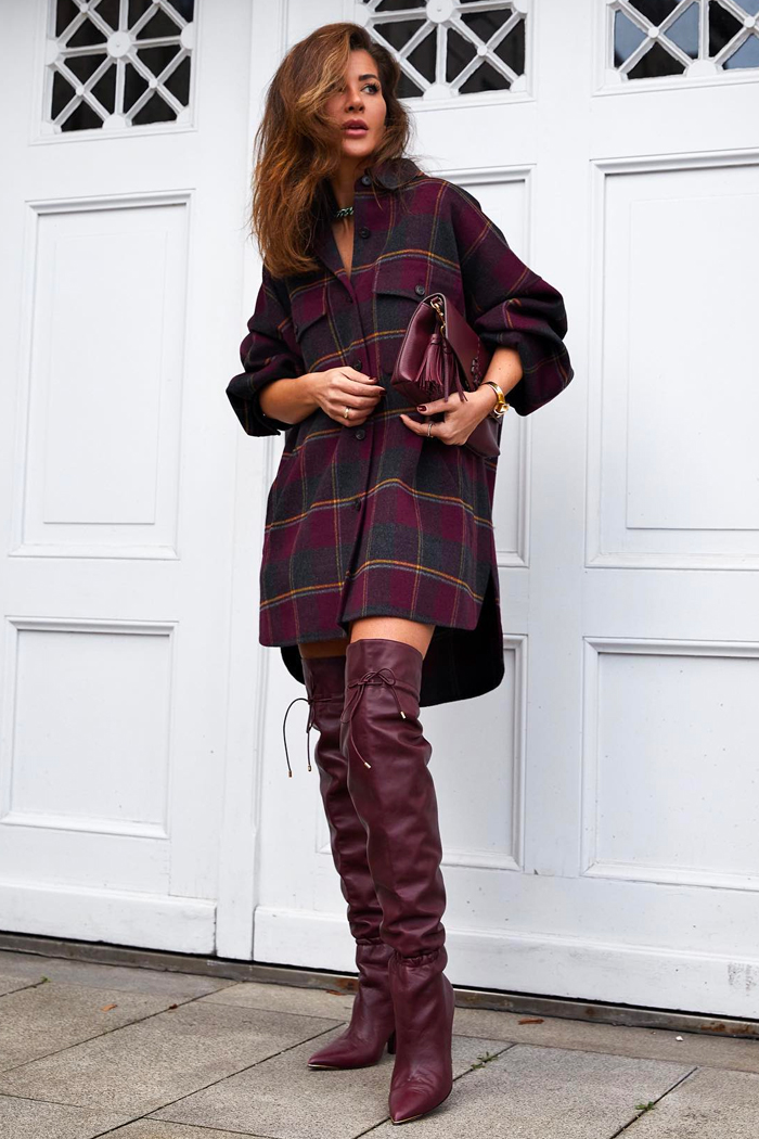 Woman wearing burgundy over-the-knee boots with a burgundy plaid shacket dress and matching handbag