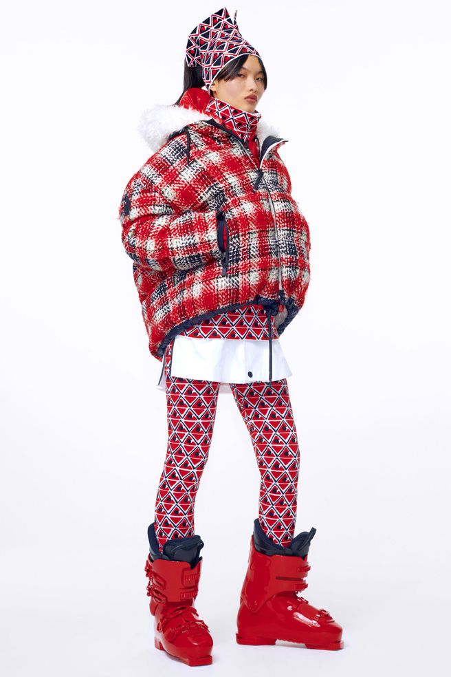 Model in a red, black and white geometric patterned ski jacket and leggings with bright red ski boots