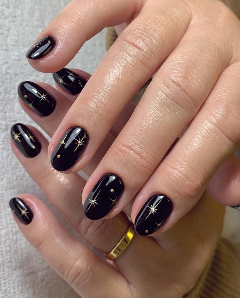 Short almond black nails with gold starburst nail art