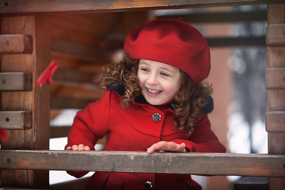 A little girl wearing a red winter coat with a red beret