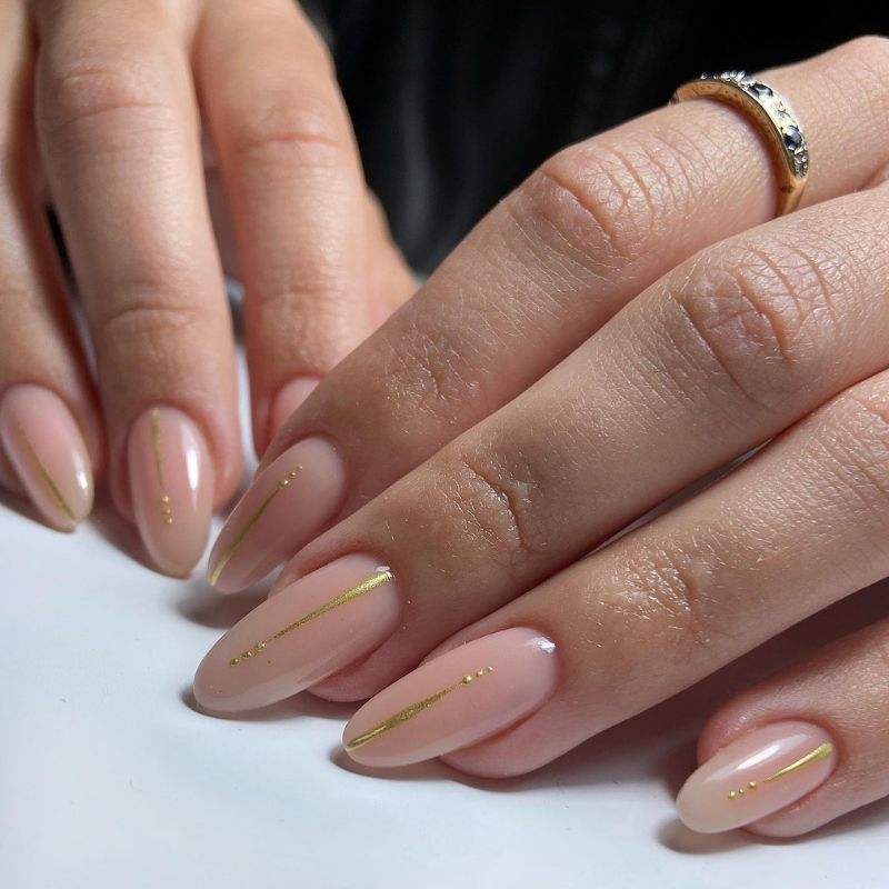 Nude almond nails with fine gold lines and tiny gold dot details