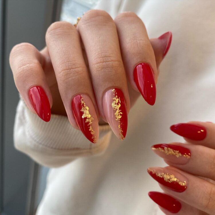 Long almond red nails with gold foil flakes in streaks on accent nails