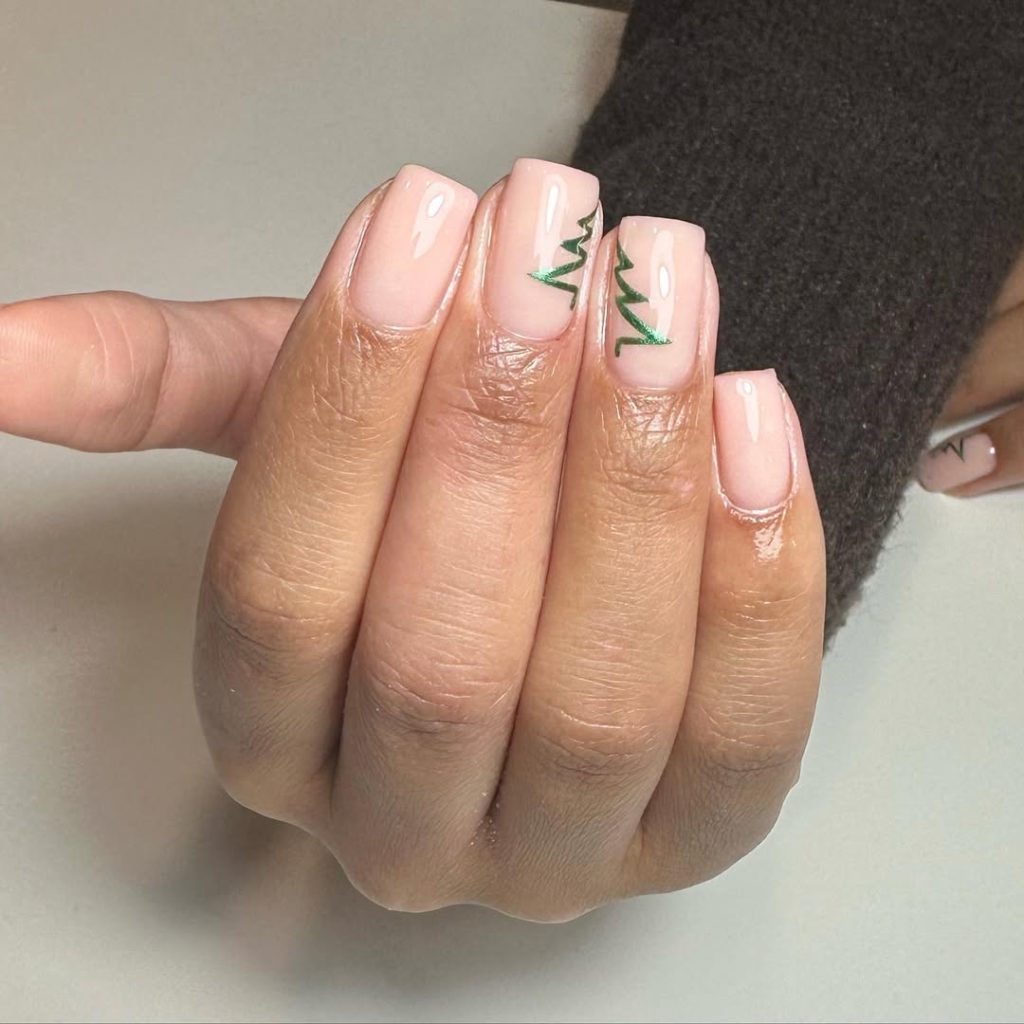 Nude oval nails with a small green Christmas tree detail