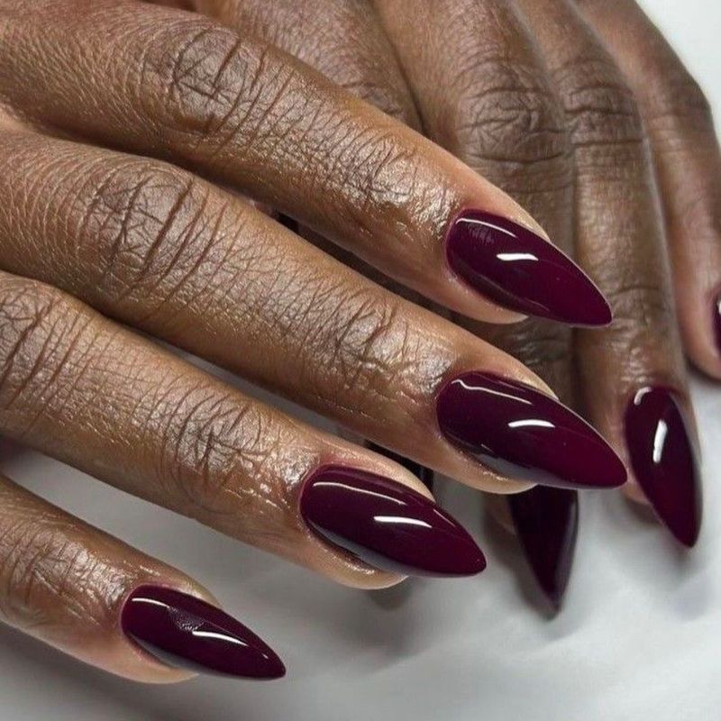 Deep burgundy stiletto nails on dark skin