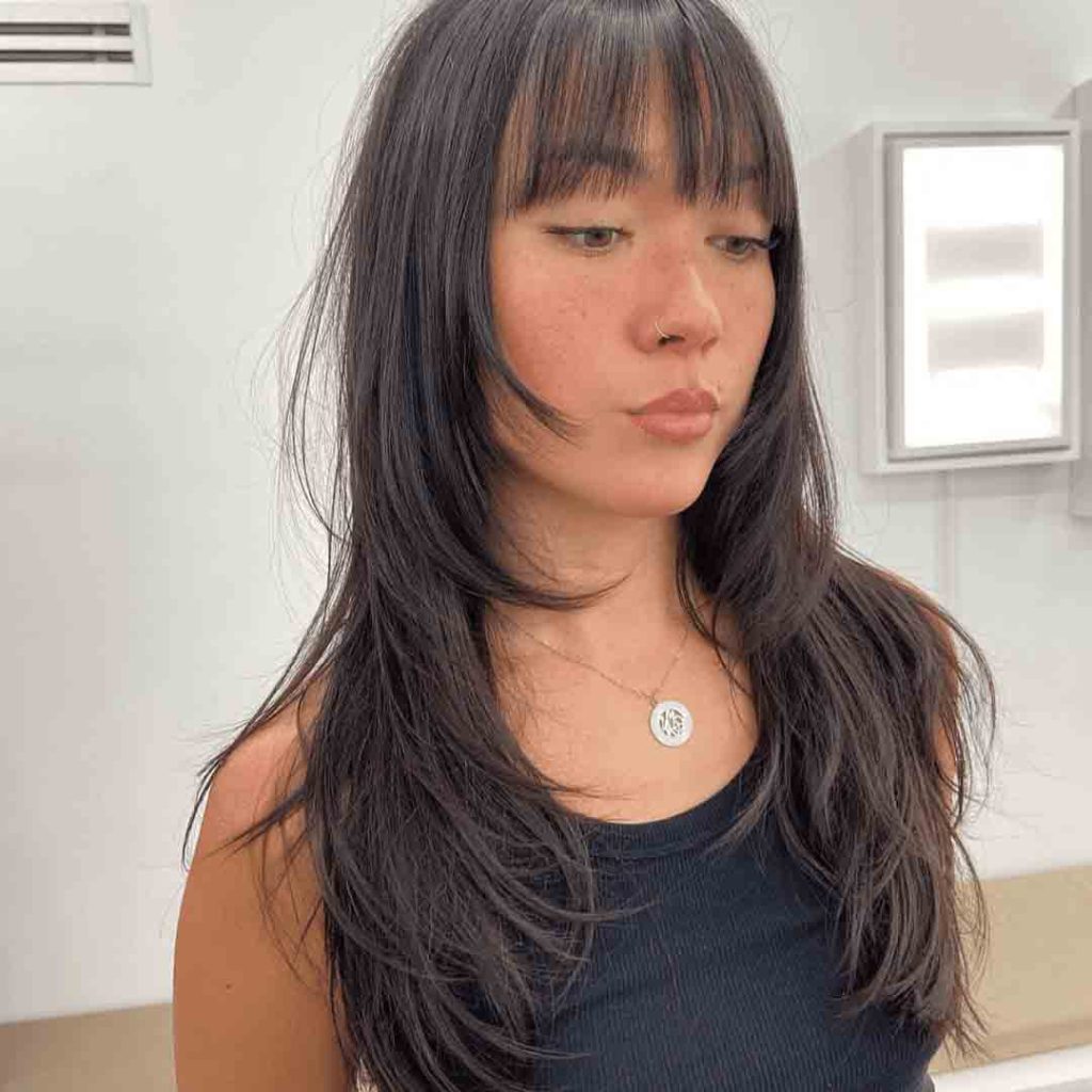 Young woman with a long wolf cut haircut and wispy bangs