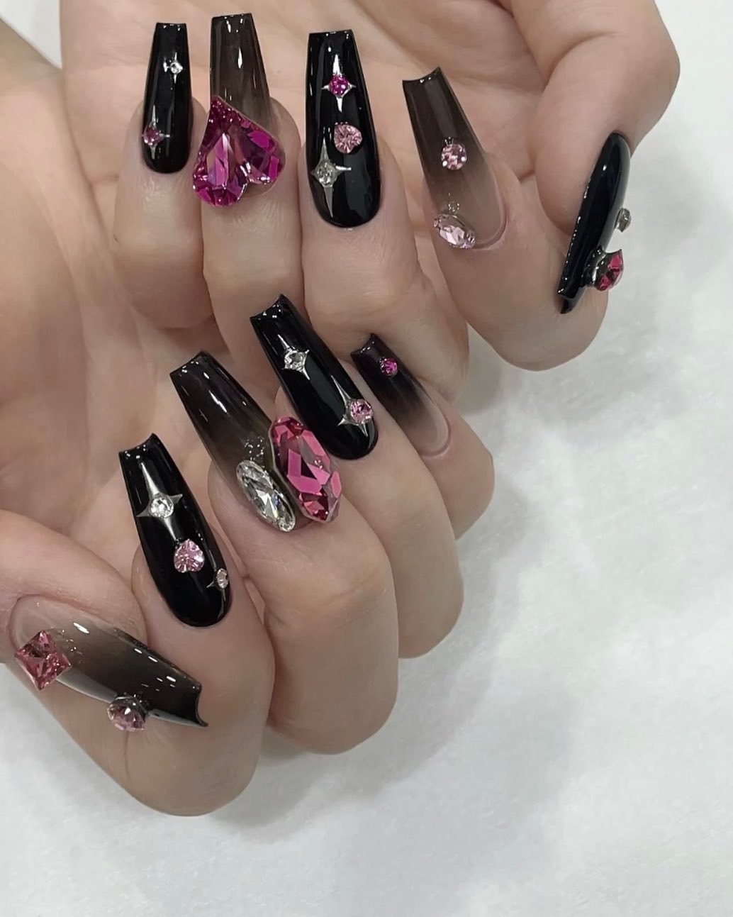 Long coffin nails in glossy black with sheer black ombre sections and pink crystal accents