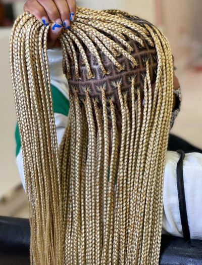 Ash blonde knotless braids held in a hand showing the color