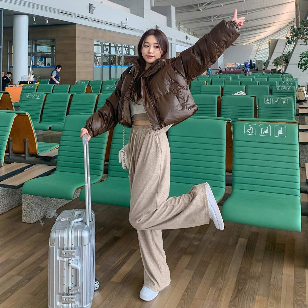 Woman in a cropped puffer jacket with a matching grey sweatsuit at the airport