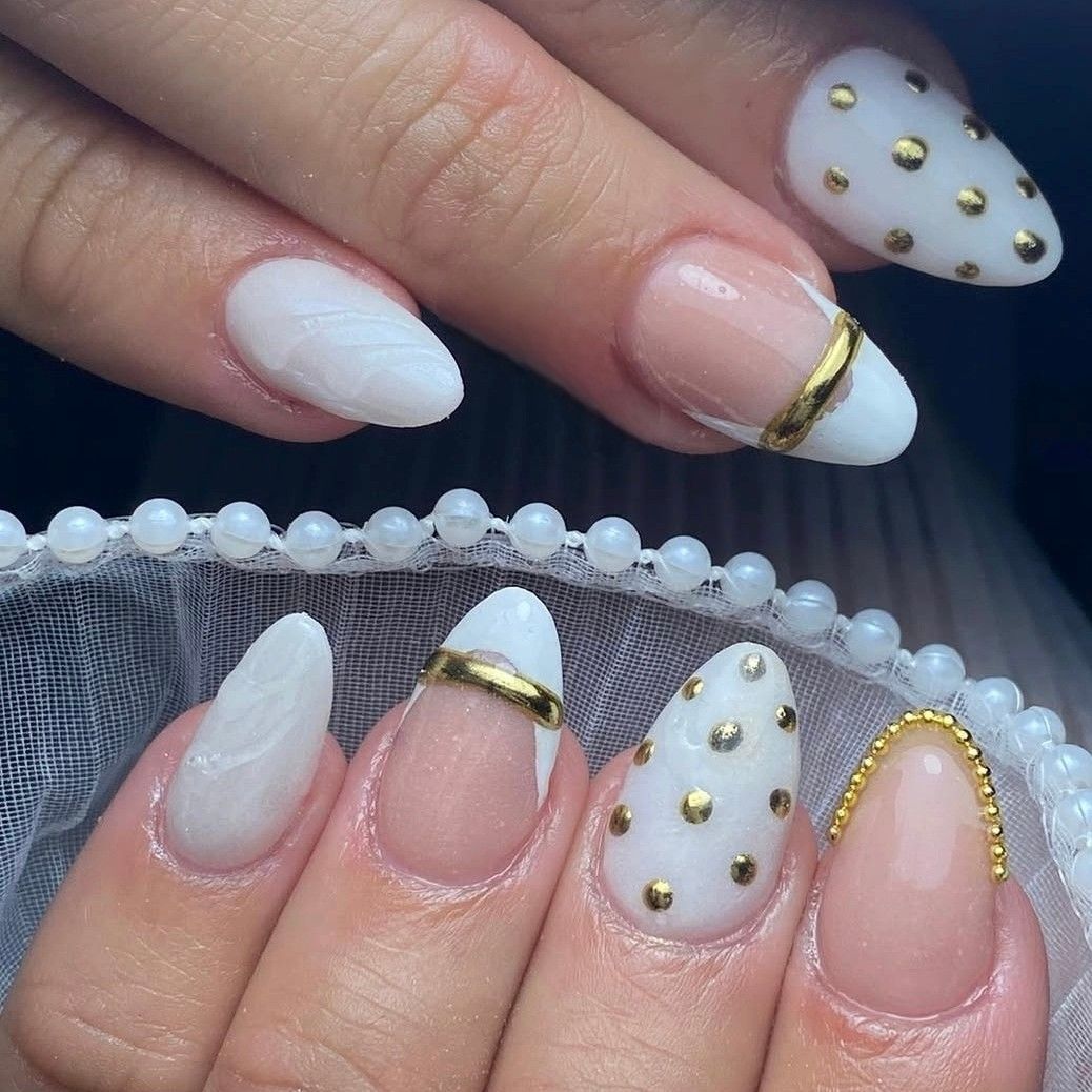Medium almond nails in white with scattered gold studs and thin gold French bands