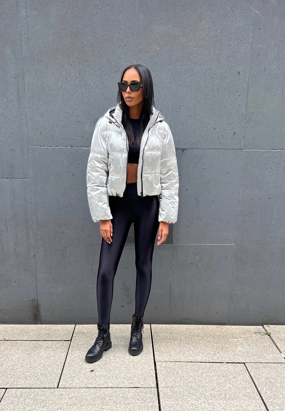 Woman in metallic silver cropped puffer jacket, black leggings and lace-up platform boots
