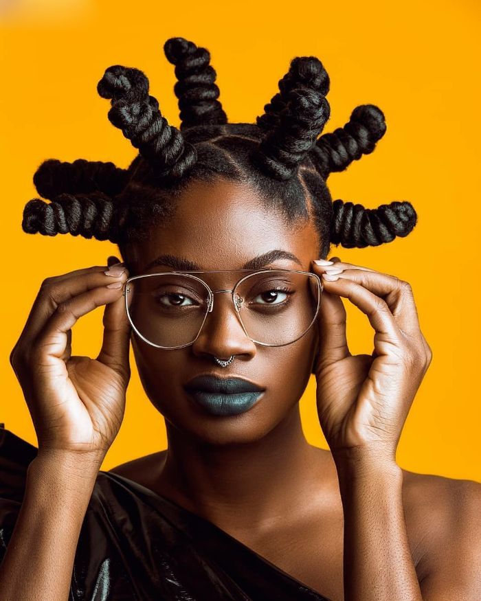 Spiked Bantu knots with sharp parting on an orange background