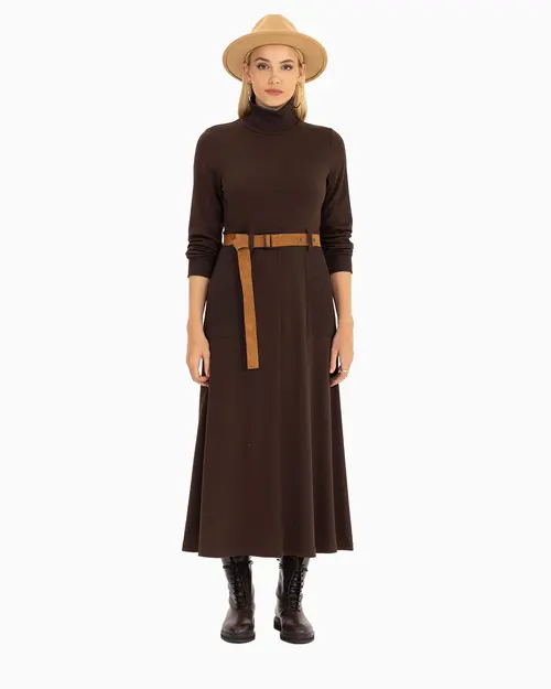 Woman in a dark brown turtleneck midi dress, tan belt, felt hat and dark brown lace-up boots