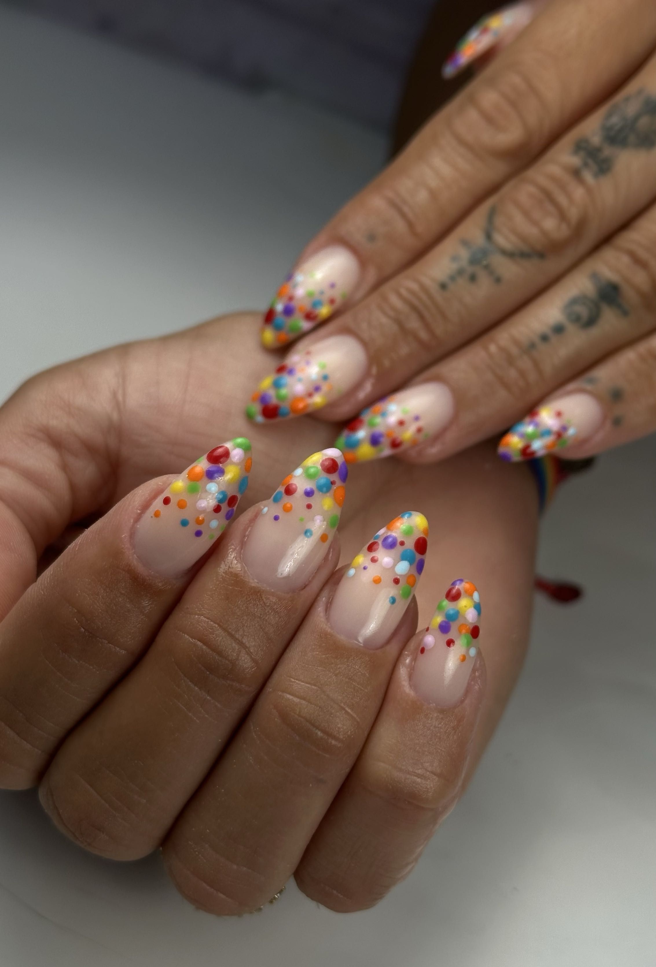 Almond nude nails with colorful confetti dot tips