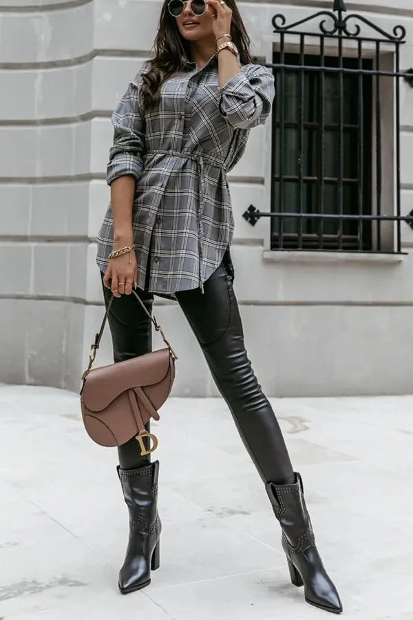 Woman wearing a grey plaid tunic shirt, black leather leggings and black heeled ankle boots