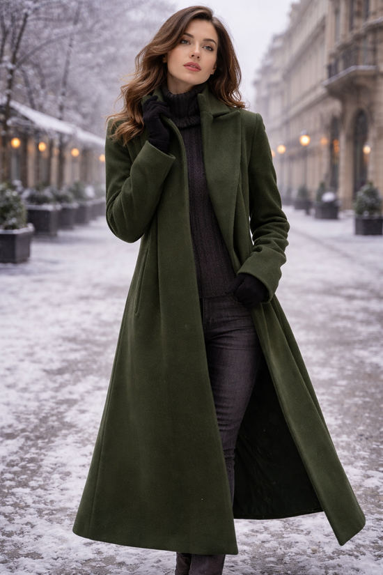 Woman wearing a long forest-green wool coat with a dark turtleneck, gray jeans and black gloves on a snowy street