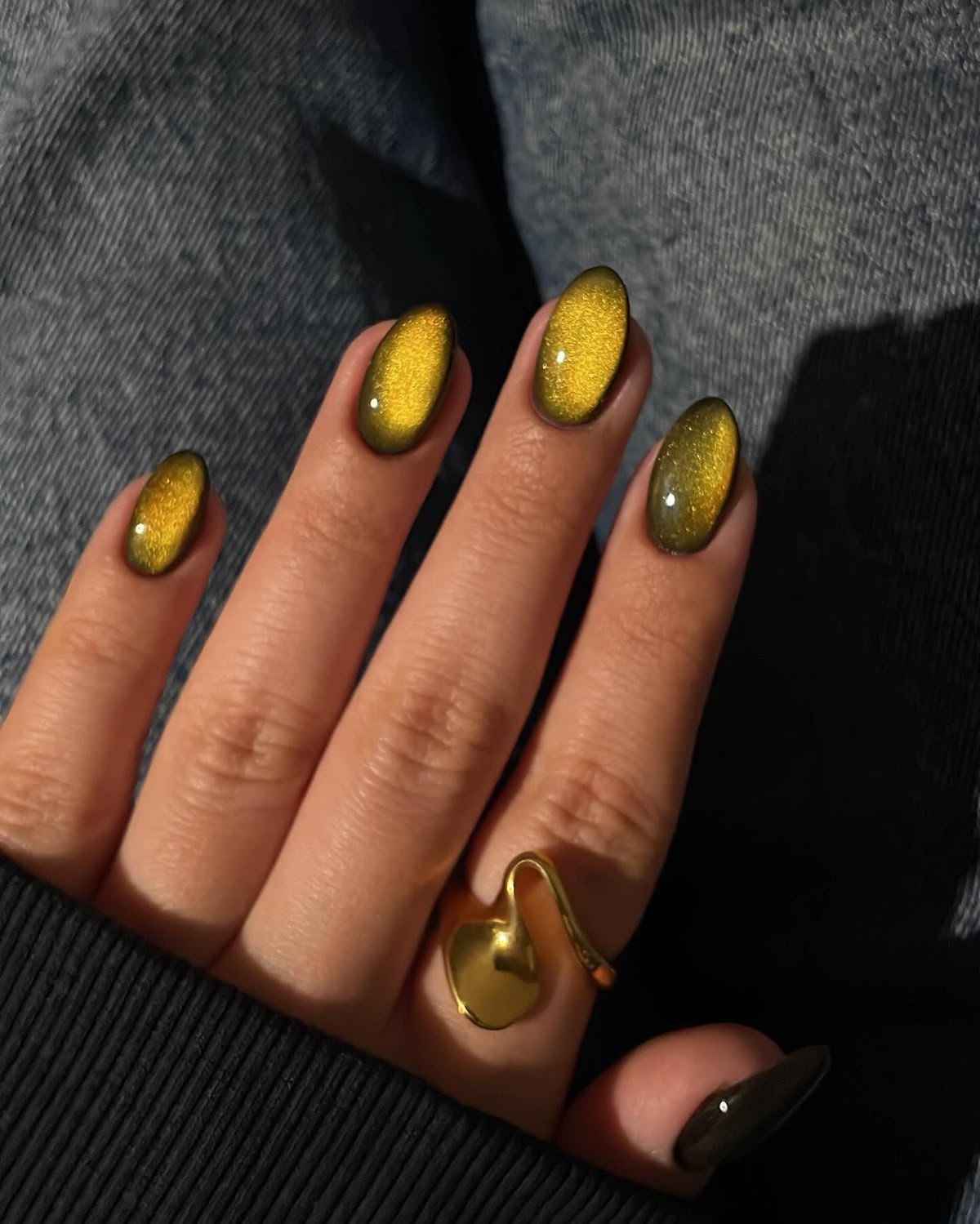 Green cat-eye almond nails with a gold magnetic band