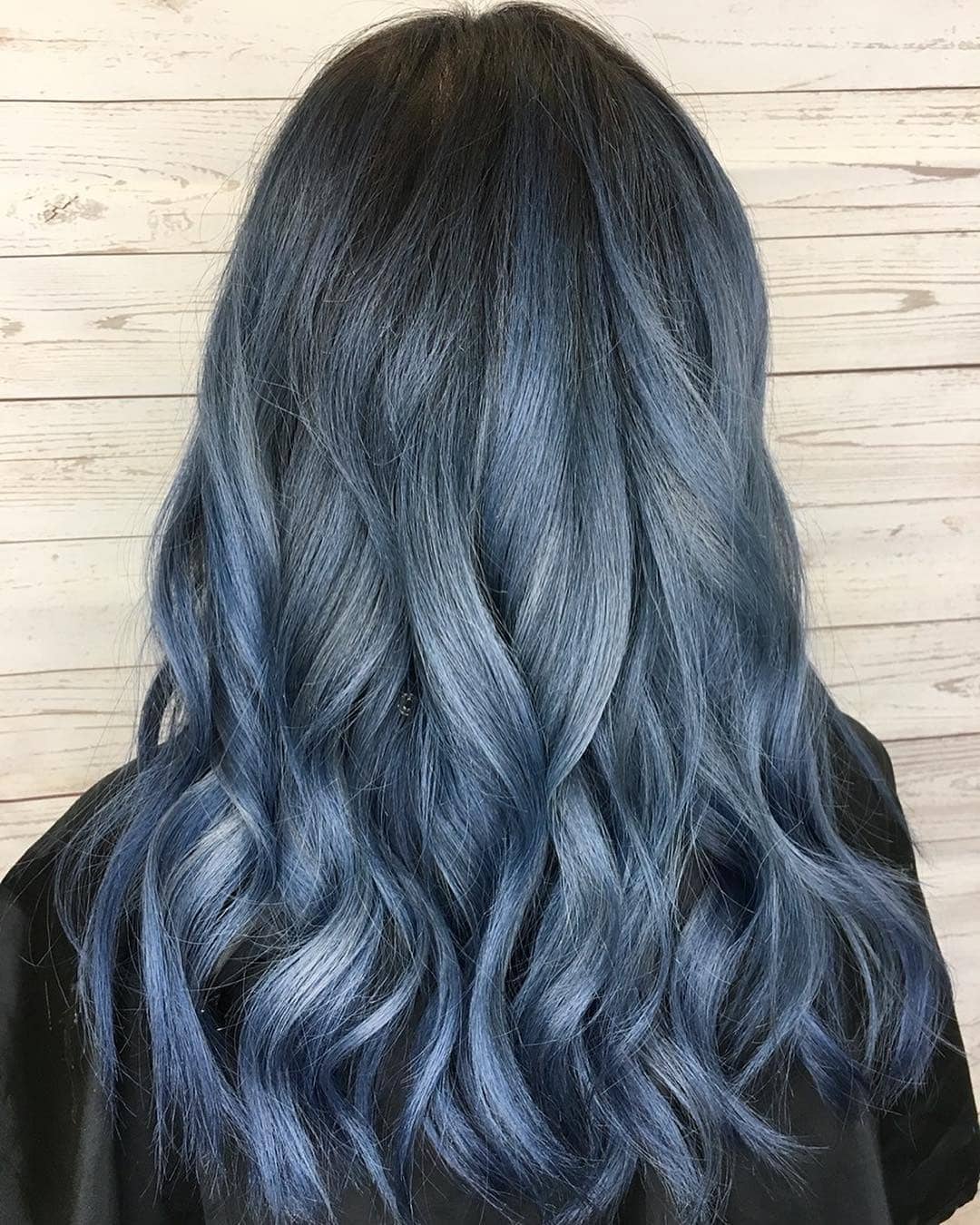 Back view of long wavy hair with dark roots melting into slate blue-grey ends