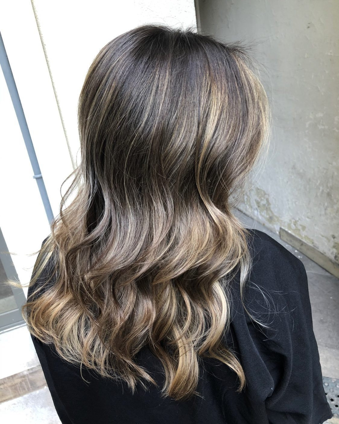Back view of long wavy hair with mushroom brown balayage and honey highlights