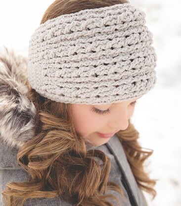 Woman with loose brown curls wearing a grey crochet headband in the snow