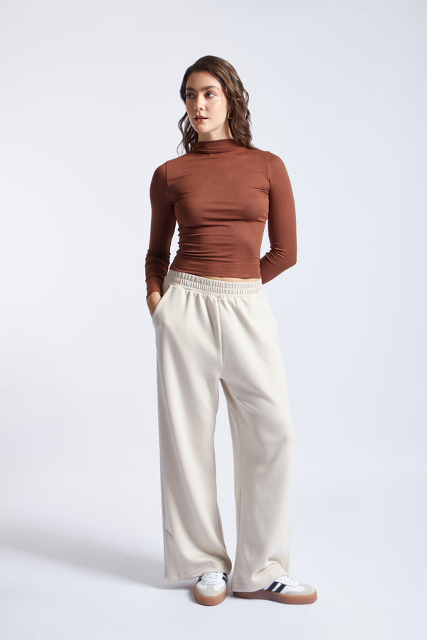 Brown ribbed turtleneck bodysuit with cream wide-leg sweatpants and sneakers