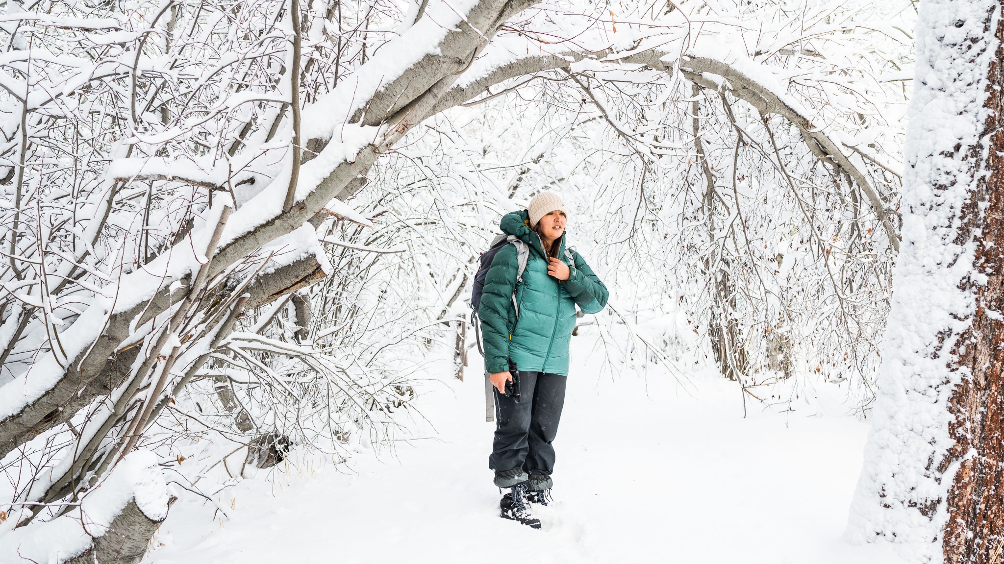 Woman wearing an insulated down jacket layered for a winter hike