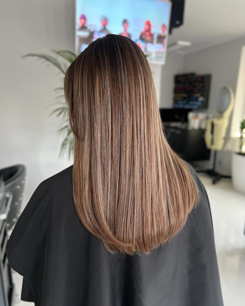 Woman with sleek light brunette hair and fine champagne blonde face-framing micro highlights