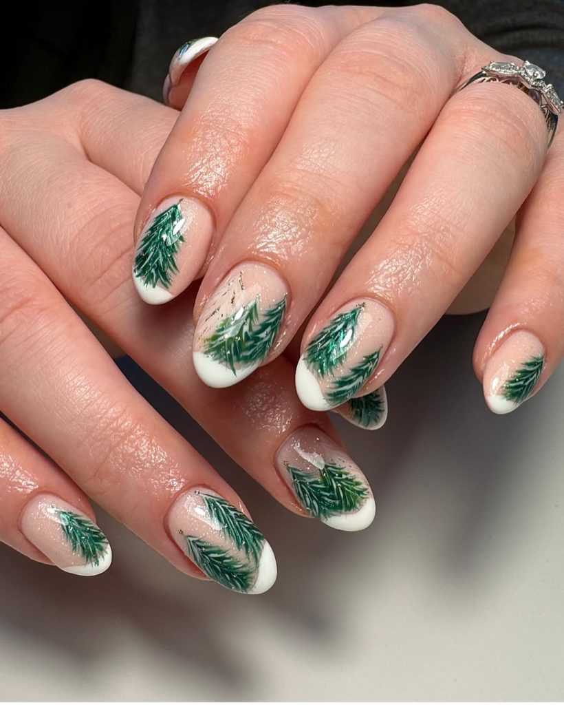 Sheer nude nails with white French tips and small hand-painted green evergreen sprigs.