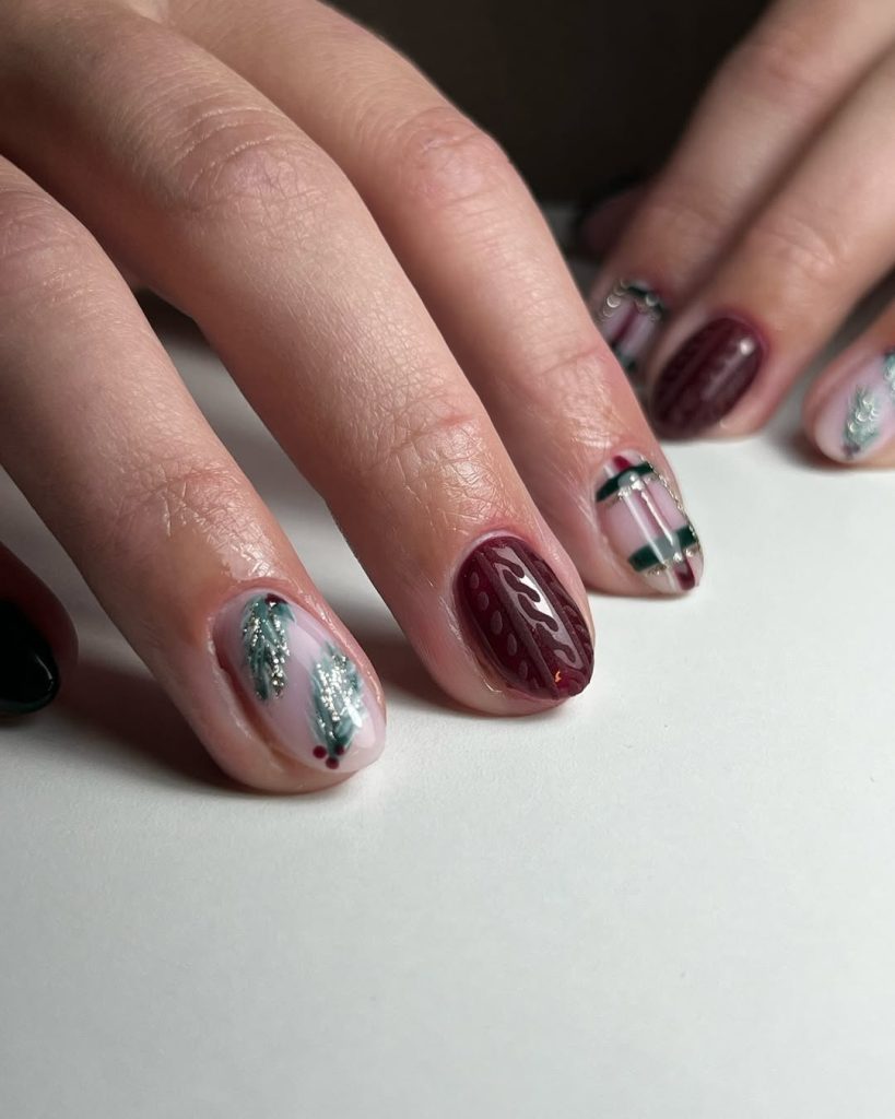 Burgundy and green nails with blush cable-knit texture and botanical leaf accents