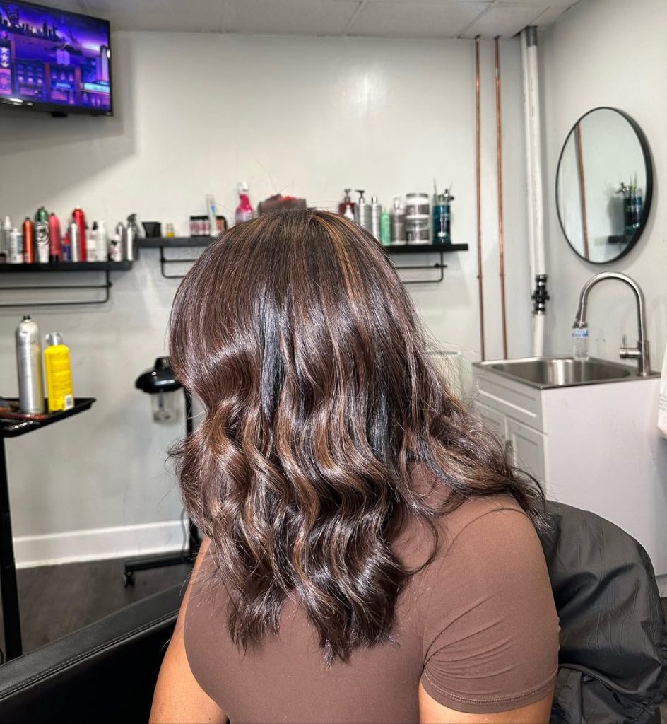 Woman with a dark chocolate bob and toffee blonde money piece flickers framing her face