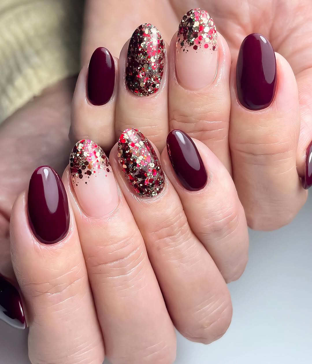Medium almond nails in deep burgundy with chunky cranberry and gold glitter fade accents
