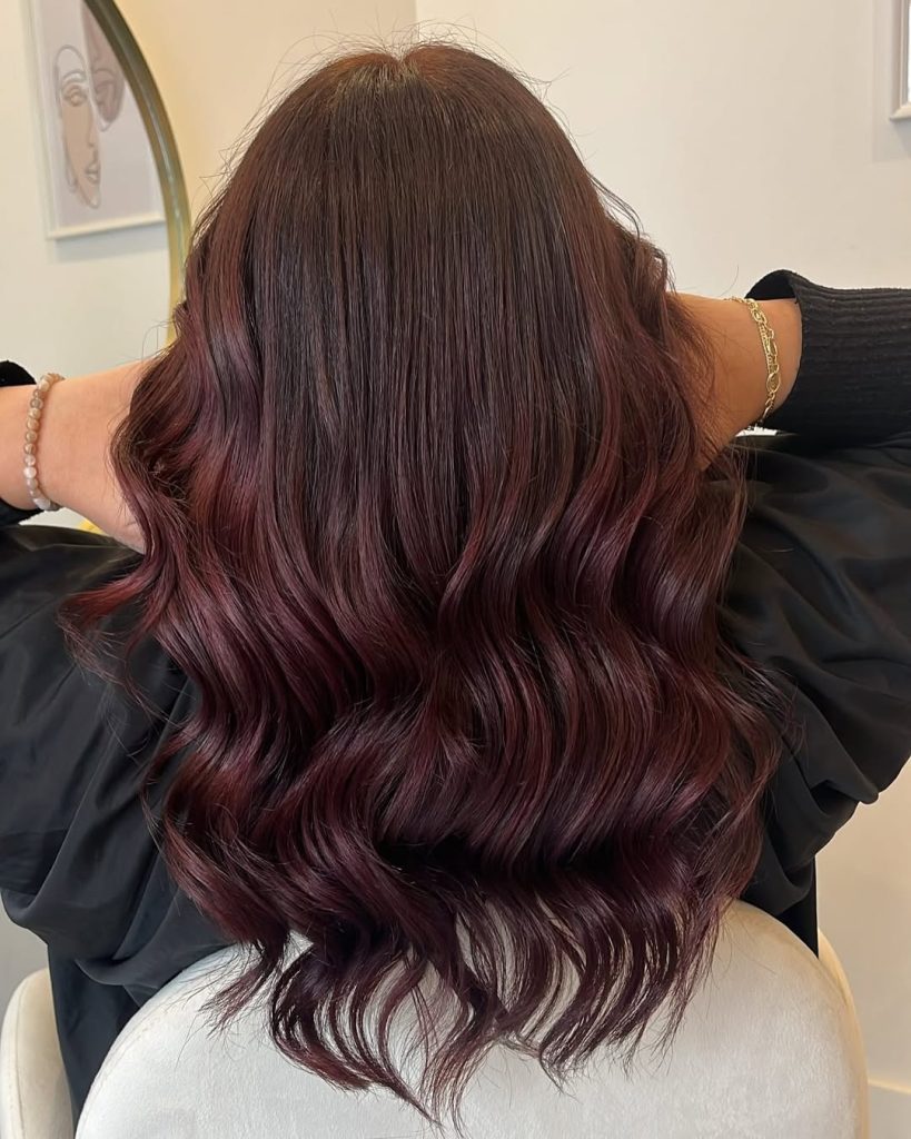 Back view of long glossy waves in subtle dark cherry cola