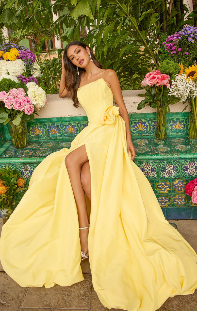 Woman wearing a yellow strapless ballgown with a waist bow and leg slit among flowers