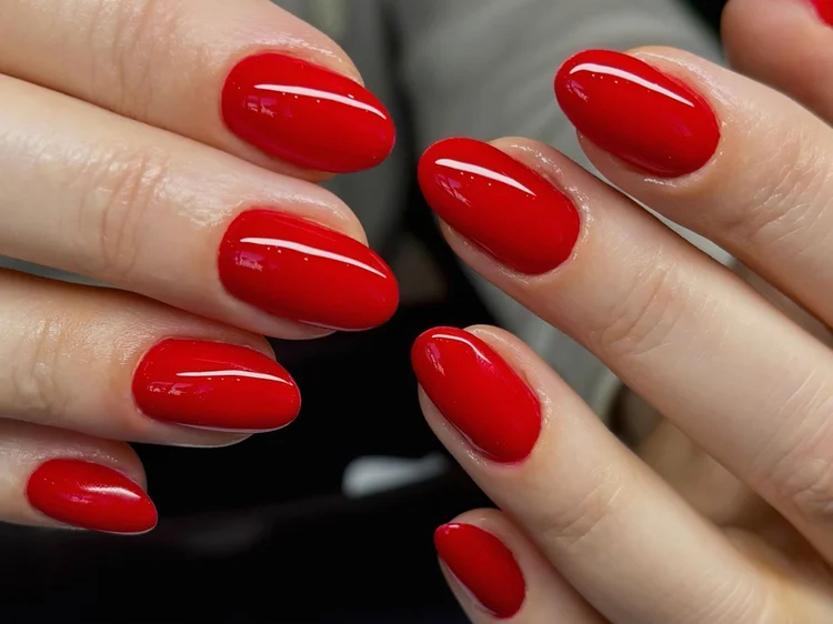 Glossy true-red creme polish on almond-shaped nails