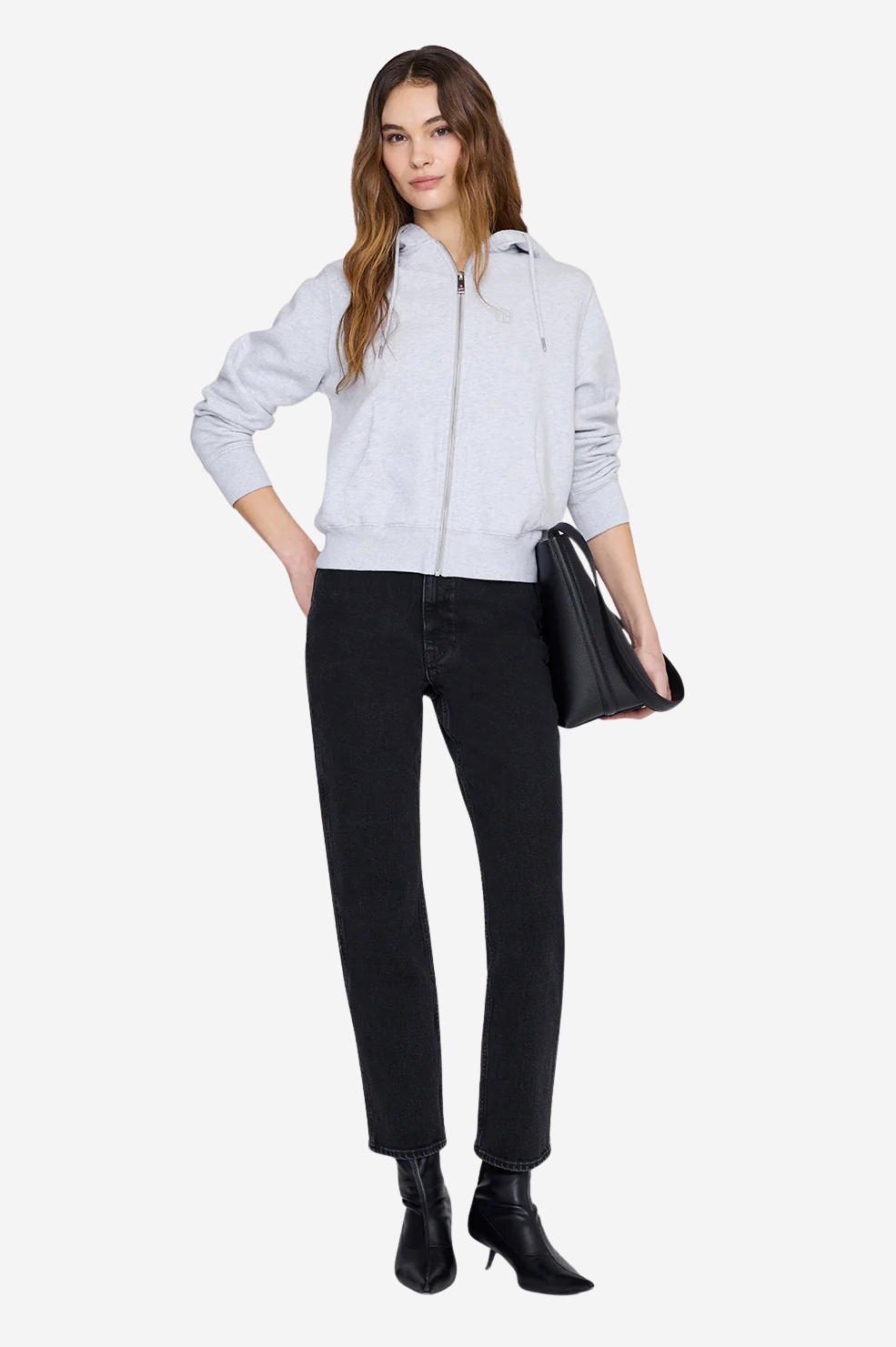 Woman in light grey zip-up hoodie, black jeans and black heeled ankle boots