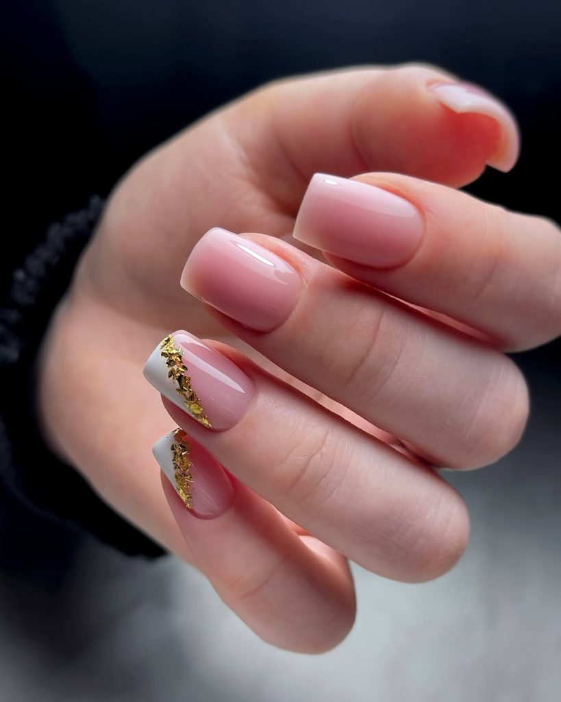 Soft pink square nails with white French tips and gold foil flakes tracing the smile line