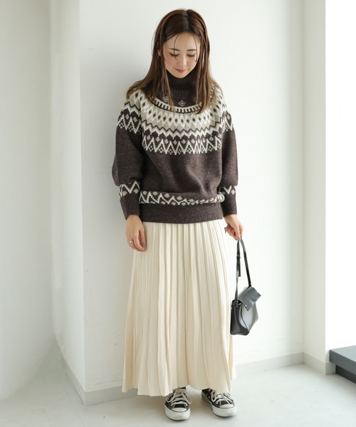 Woman wearing a brown fair-isle turtleneck sweater with a cream pleated maxi skirt and sneakers