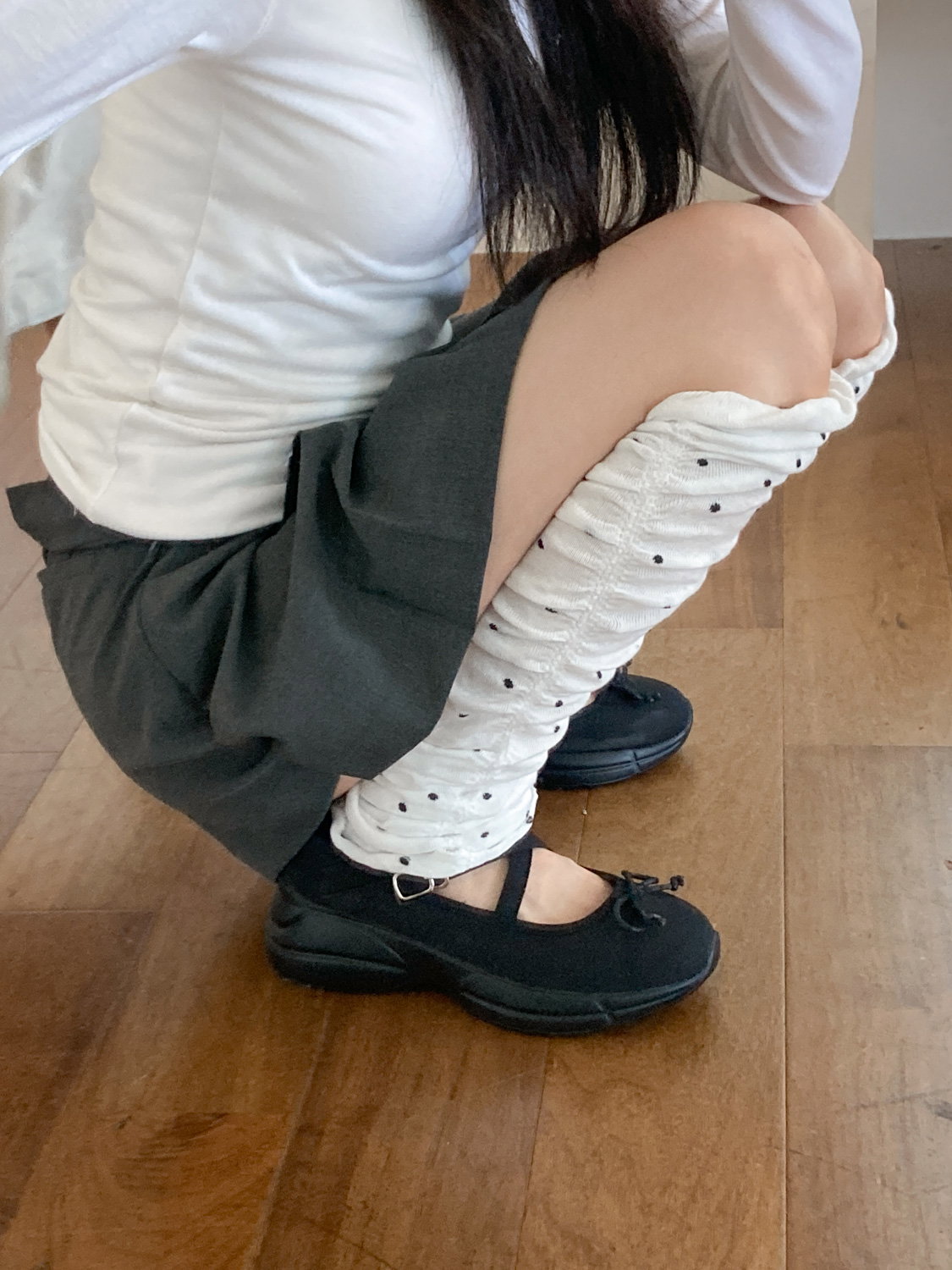 White leg warmers with black polka dots worn with black Mary Jane flats and a dark mini skirt