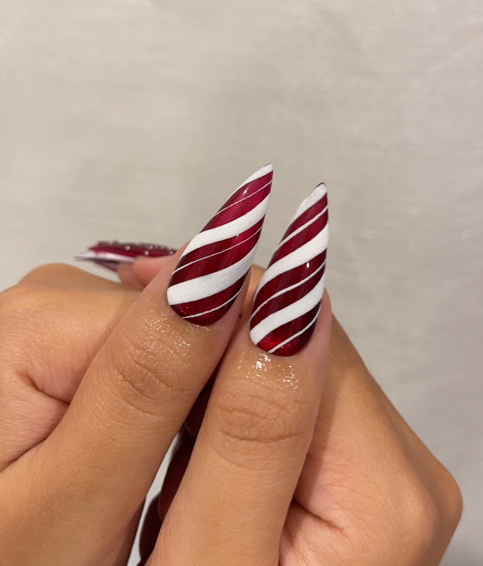 Candy cane red and white swirled stripes on long stiletto nails